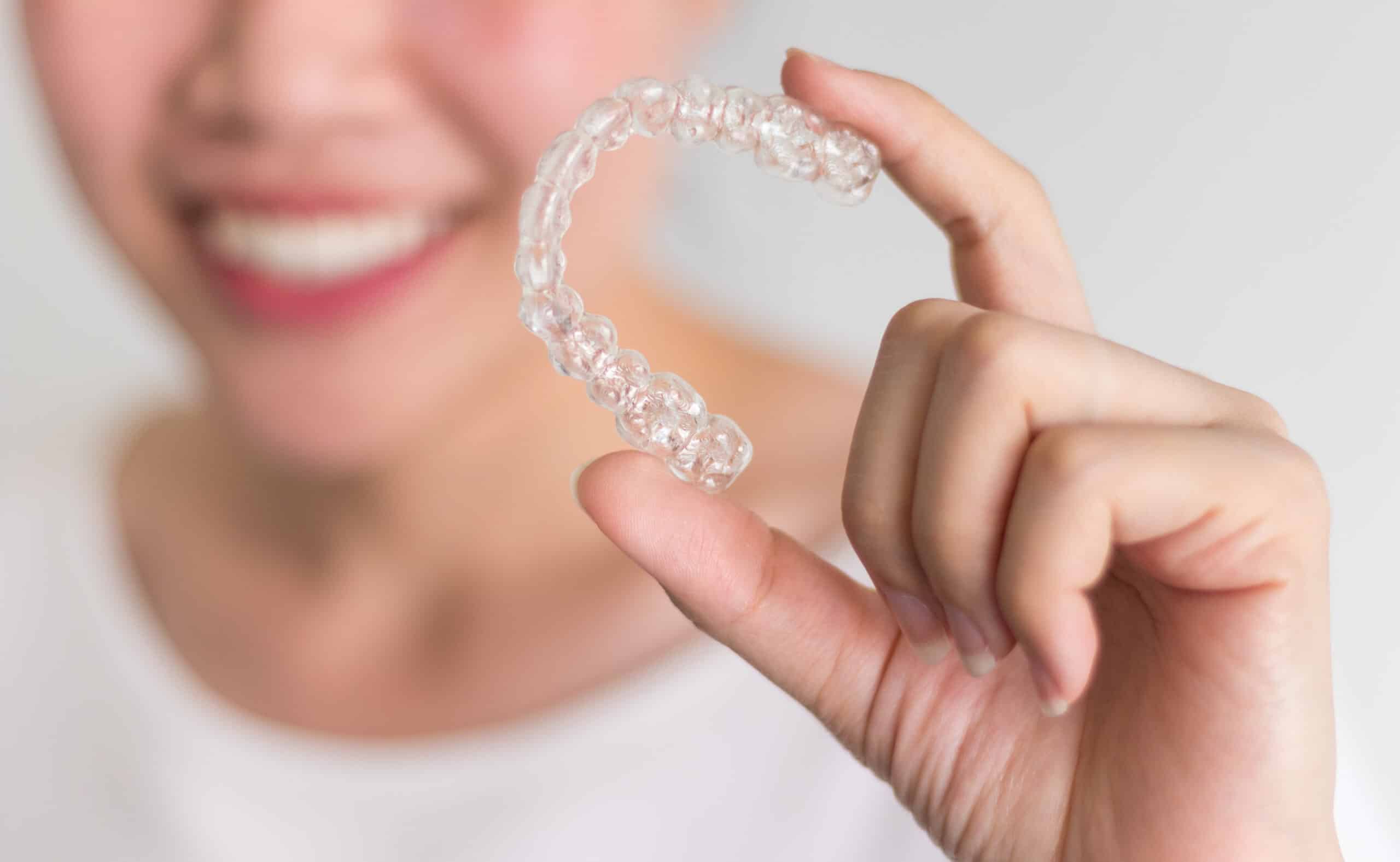 A,Smiling,Woman,Holding,Invisalign,Or,Invisible,Braces,,Orthodontic,Equipment